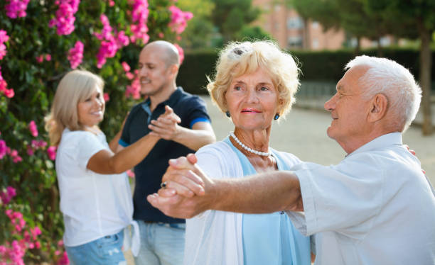 Happy cheerful positive adult friends dancing pair dance in garden